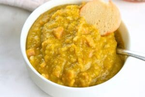 A small bowl of split pea soup, shown garnished with a bagel chip
