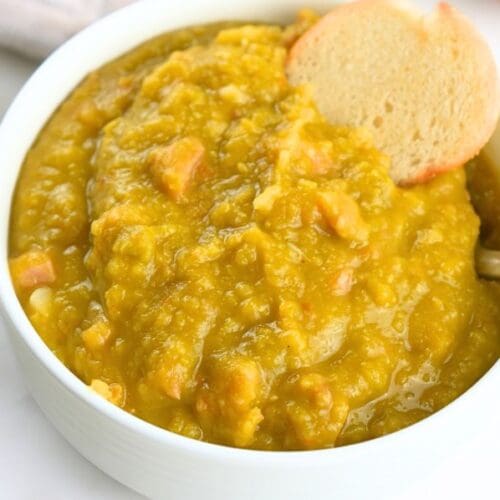 A small bowl of split pea soup, shown garnished with a bagel chip
