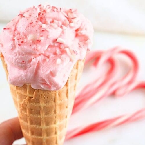 A peppermint ice cream cone with candy canes in background