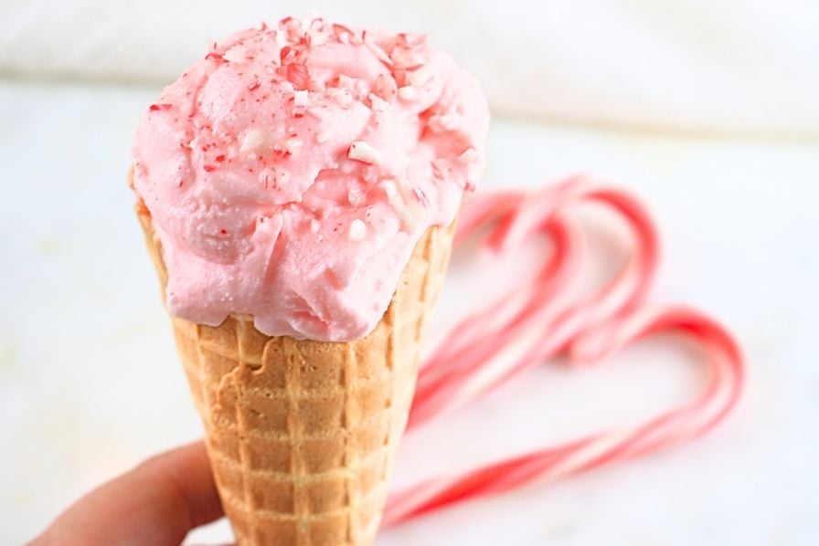 A peppermint ice cream cone with candy canes in background