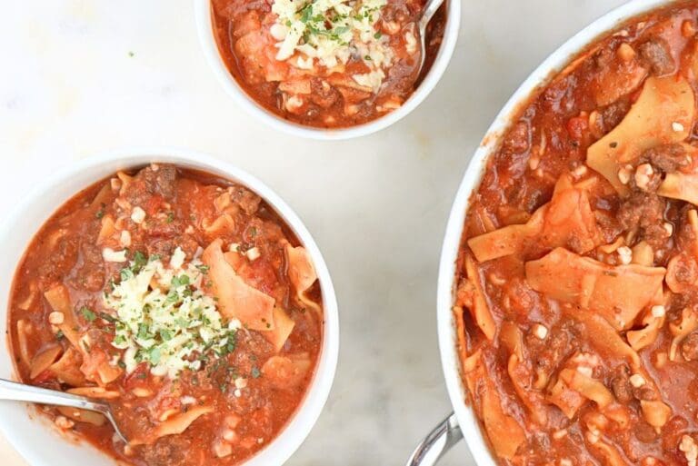 Bowls of slow cooker lasagna soup next to a large pot