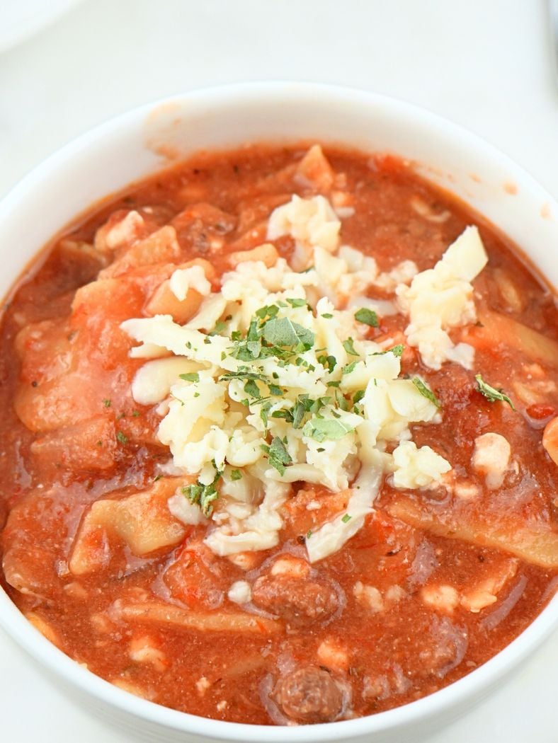 A small bowl of slow cooker lasagna soup with cheese and herbs on top