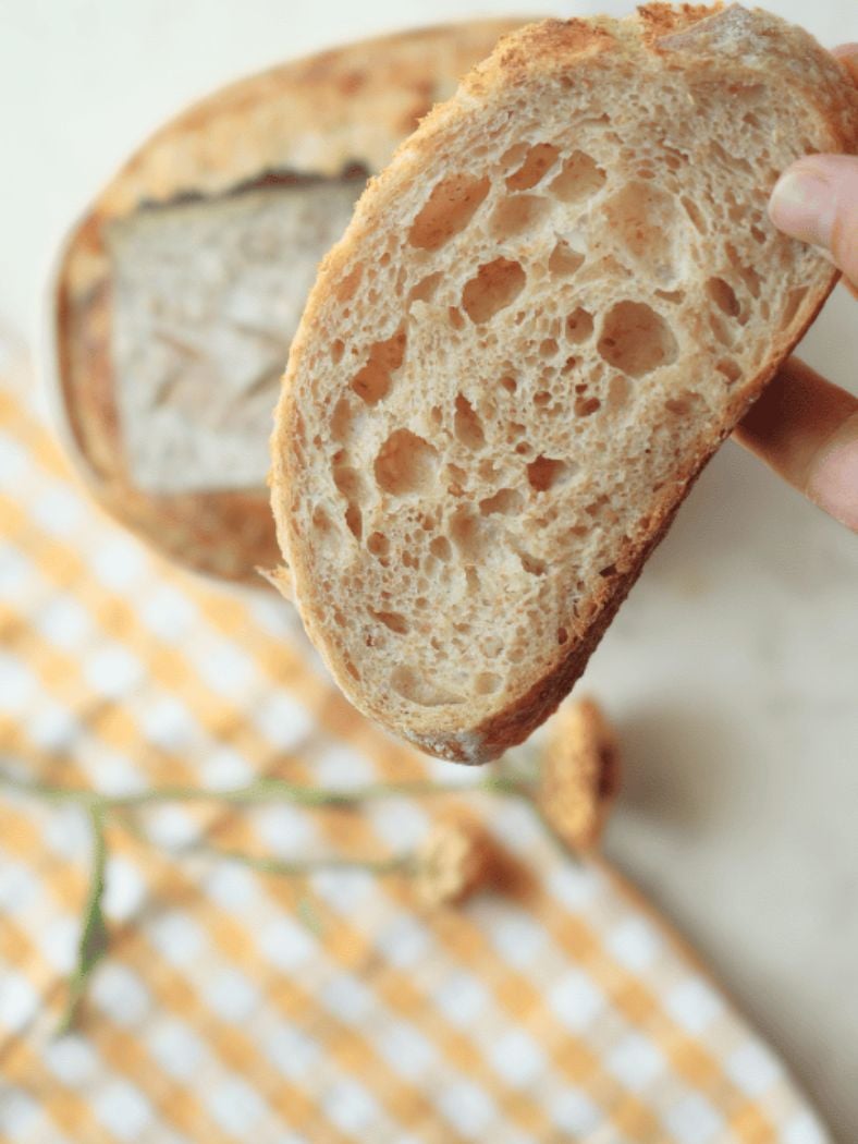 Slices of sourdough bread with flowers and a gingham towel in the background