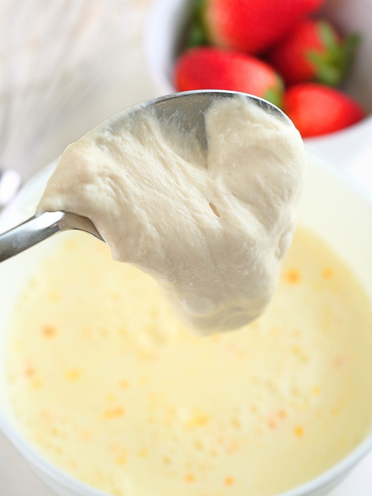 Sourdough starter being spooned into buttermilk mixture.
