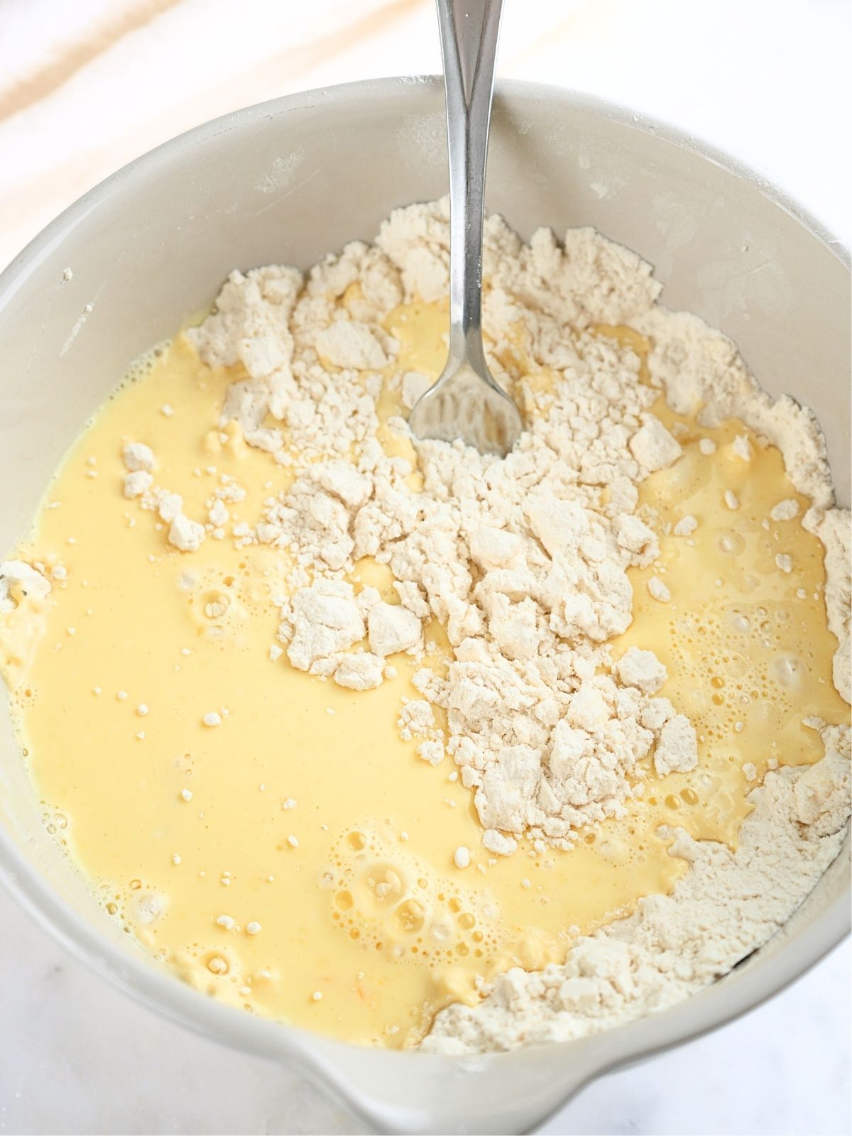 Butter milk mixture and dry ingredients in a mixing bowl, shown with a fork.