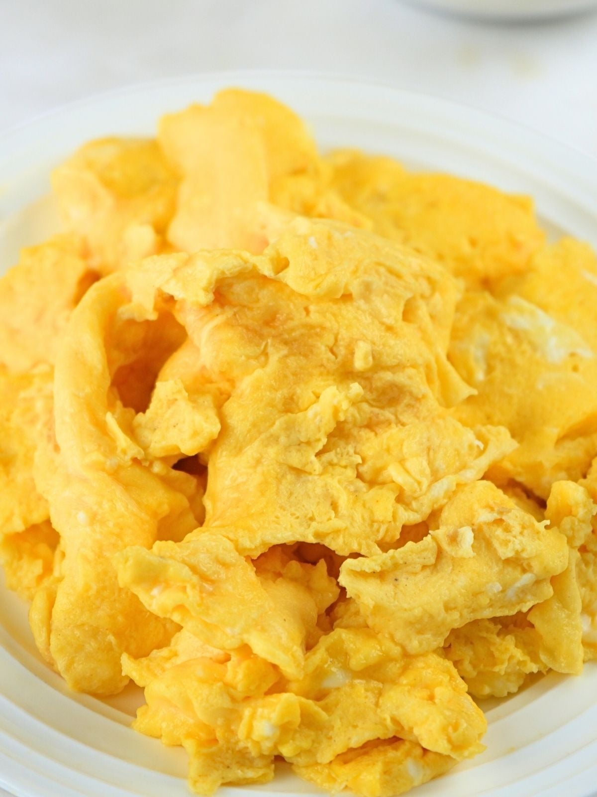 Fluffy scrambled eggs on a white plate.