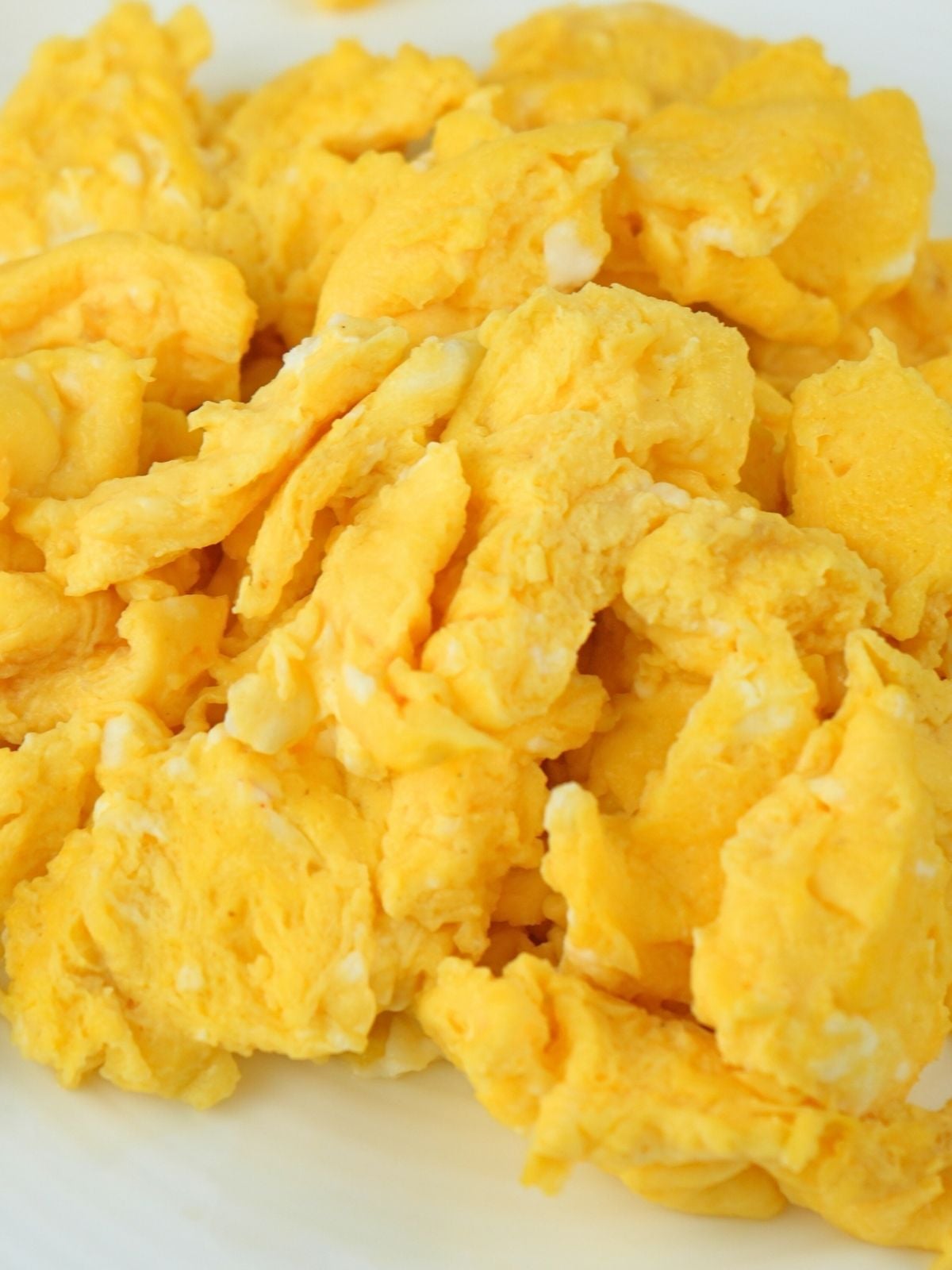 Close up of scrambled eggs on a white plate.