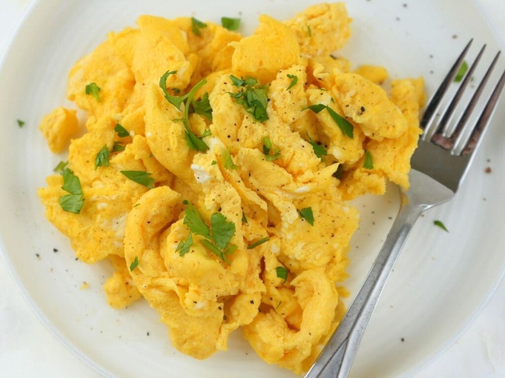 Fluffy scrambled eggs garnished with fresh herbs.