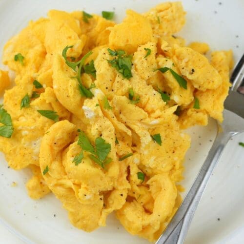 Fluffy scrambled eggs garnished with fresh herbs.