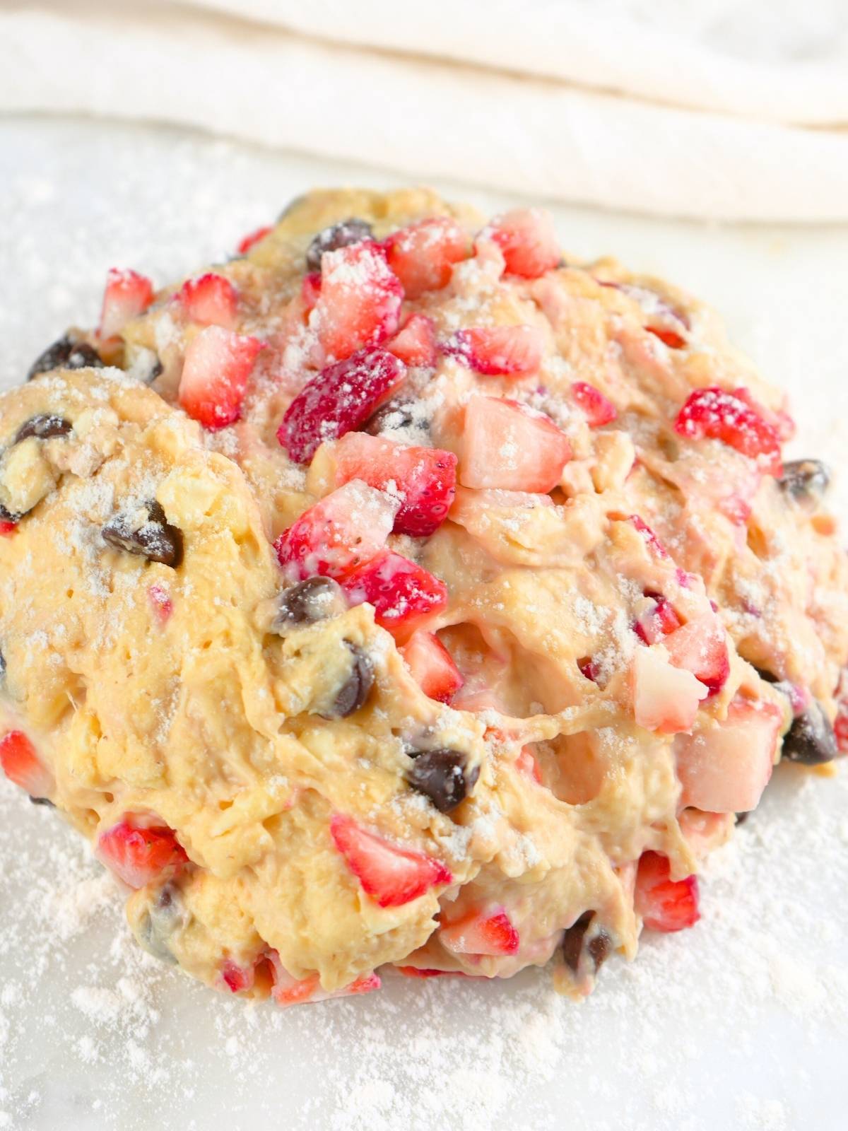 Strawberry chocolate chips sourdough scone dough on a floured surface.