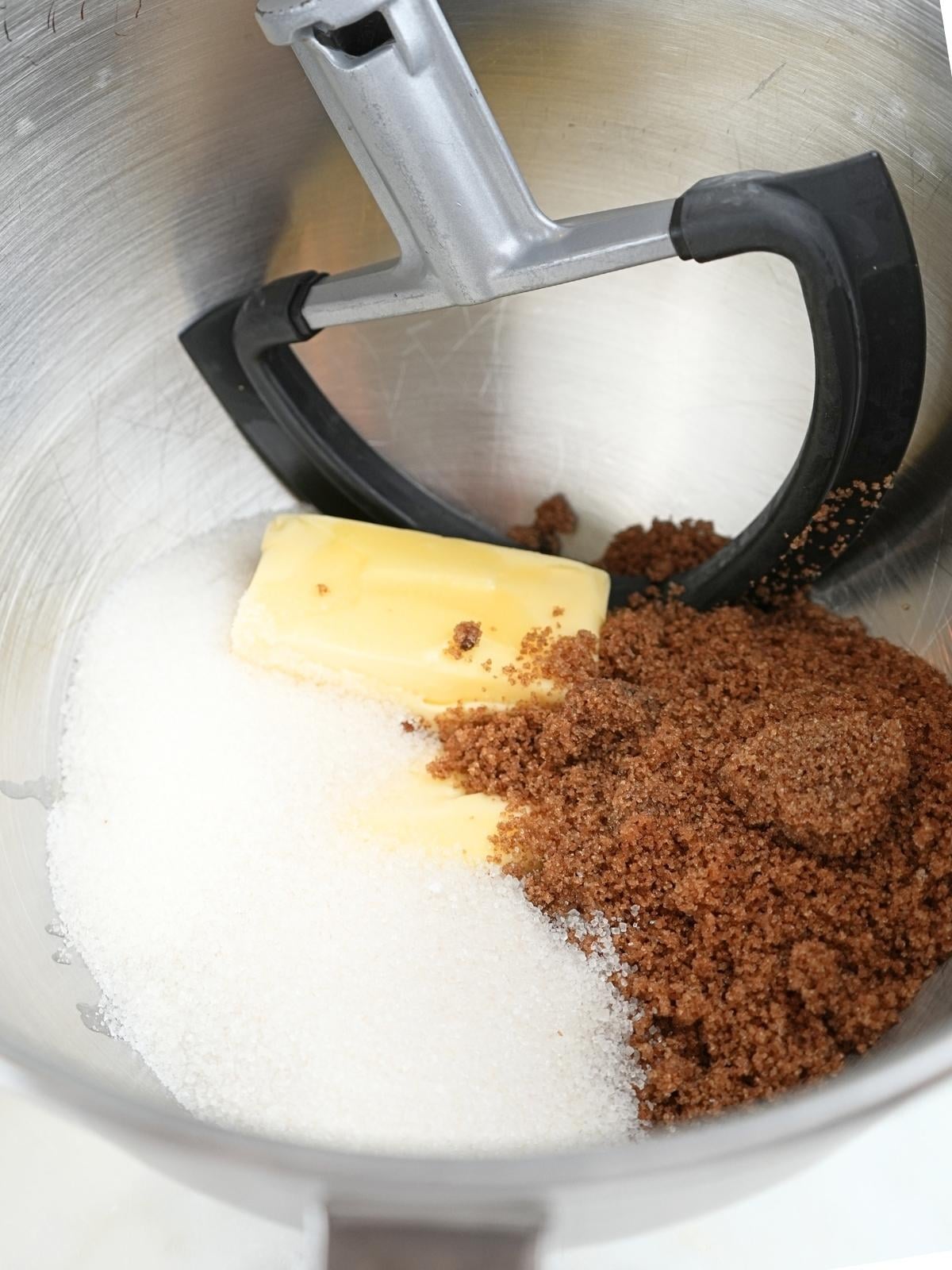 Butter, white sugar, and brown sugar in a stand mixer bowl.