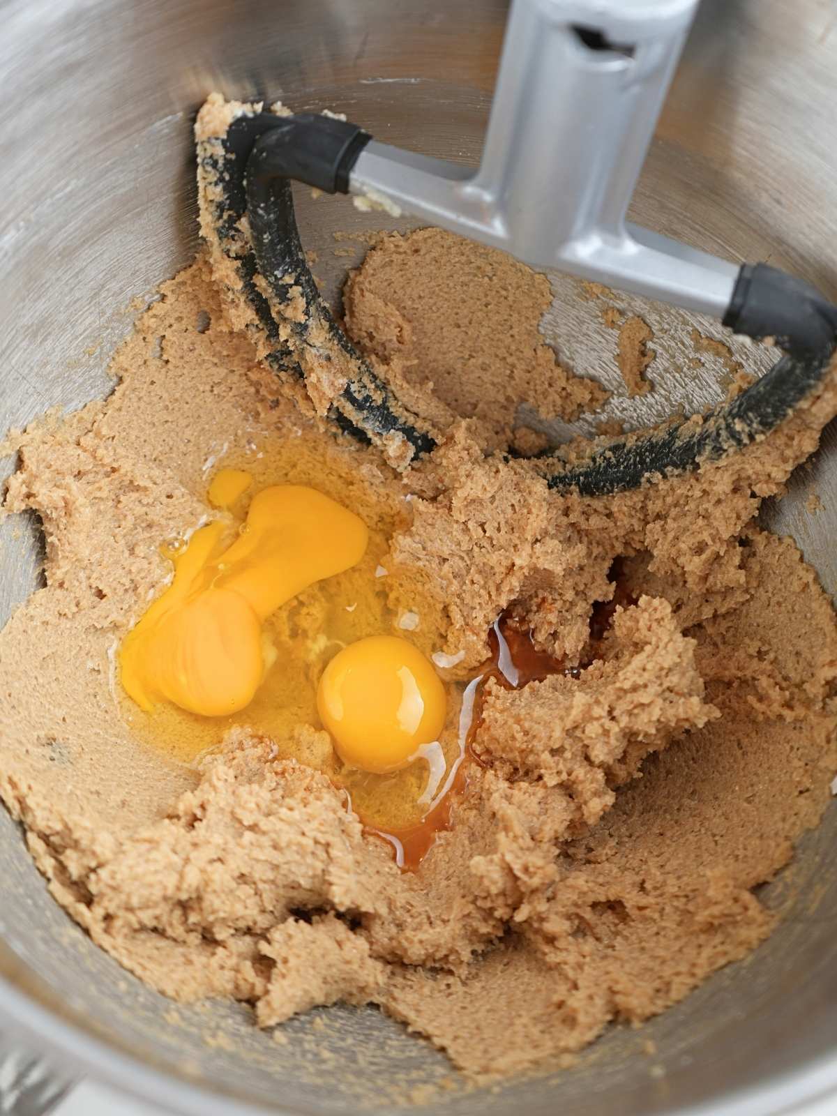 Eggs and vanilla in bowl with creamed butter and sugar.