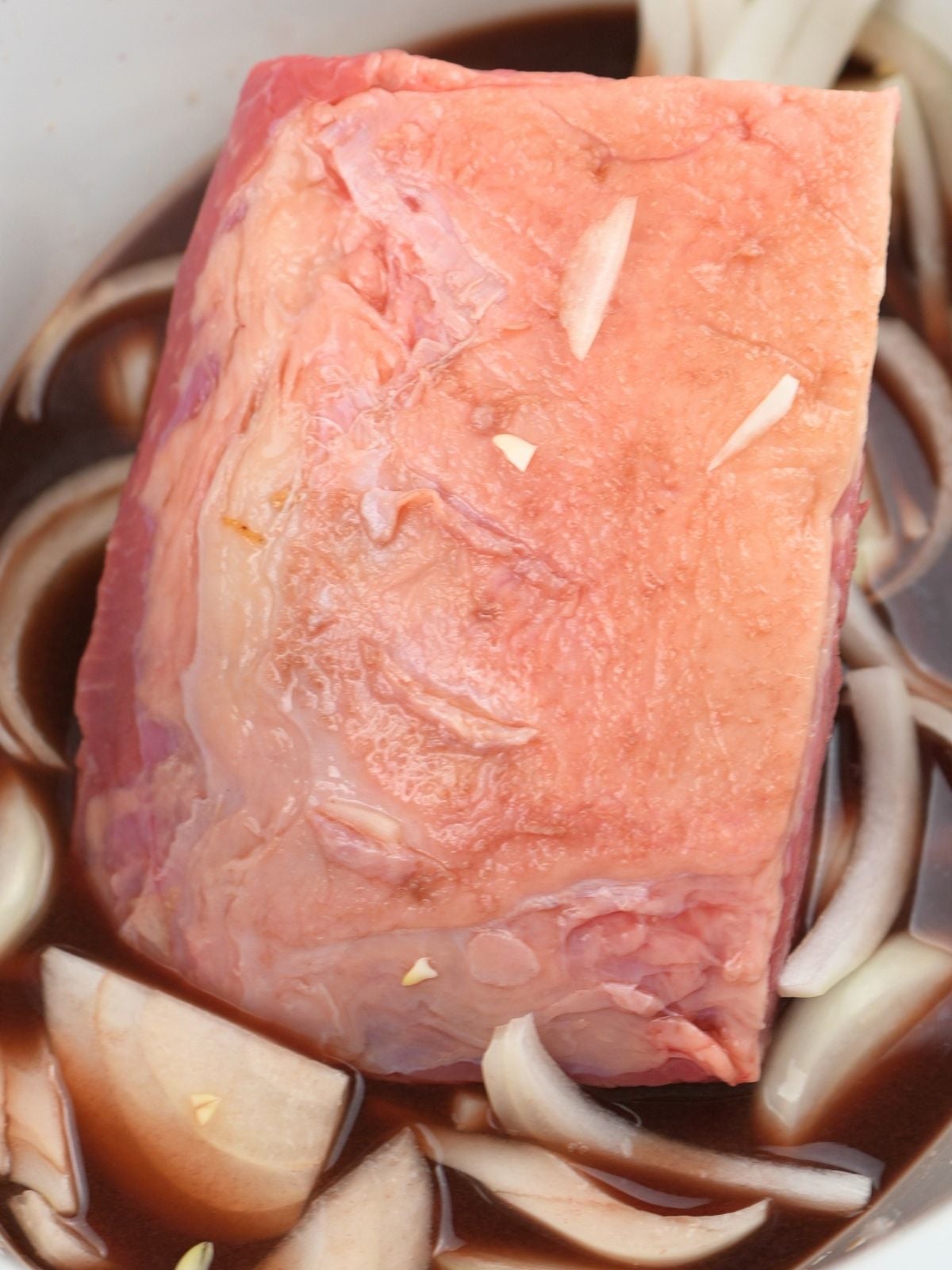 Chuck roast and onions in a slow cooker insert.