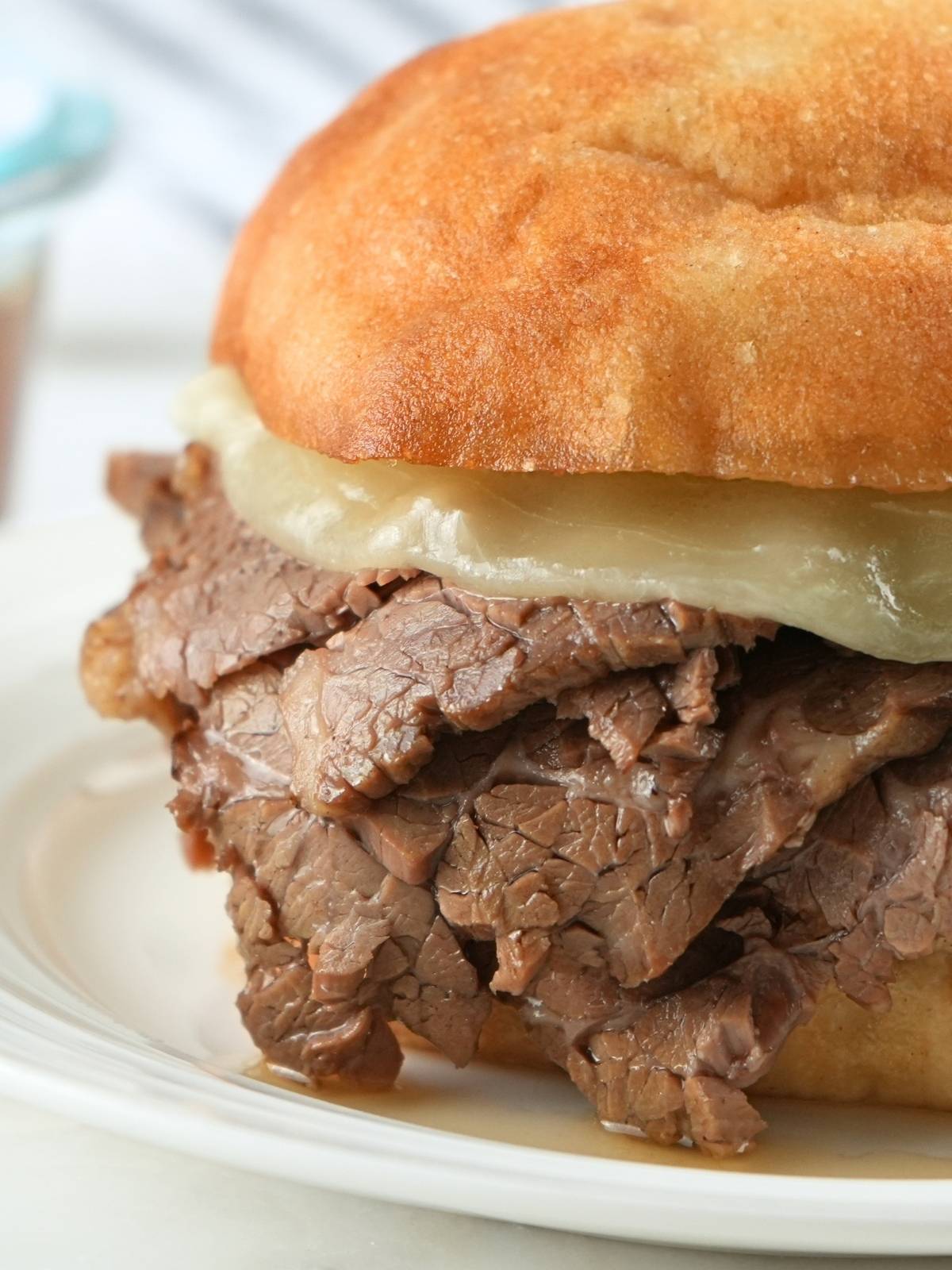 French dip sandwich with cheese on a plate.