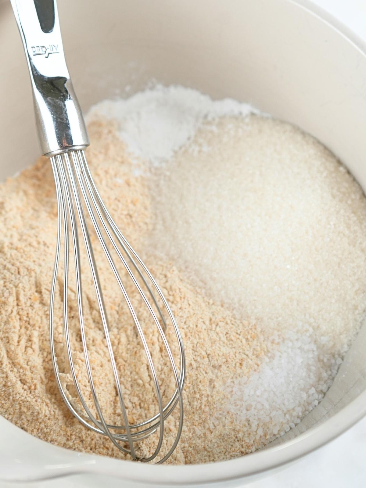 Dry ingredients in a mixing bowl with a whisk.