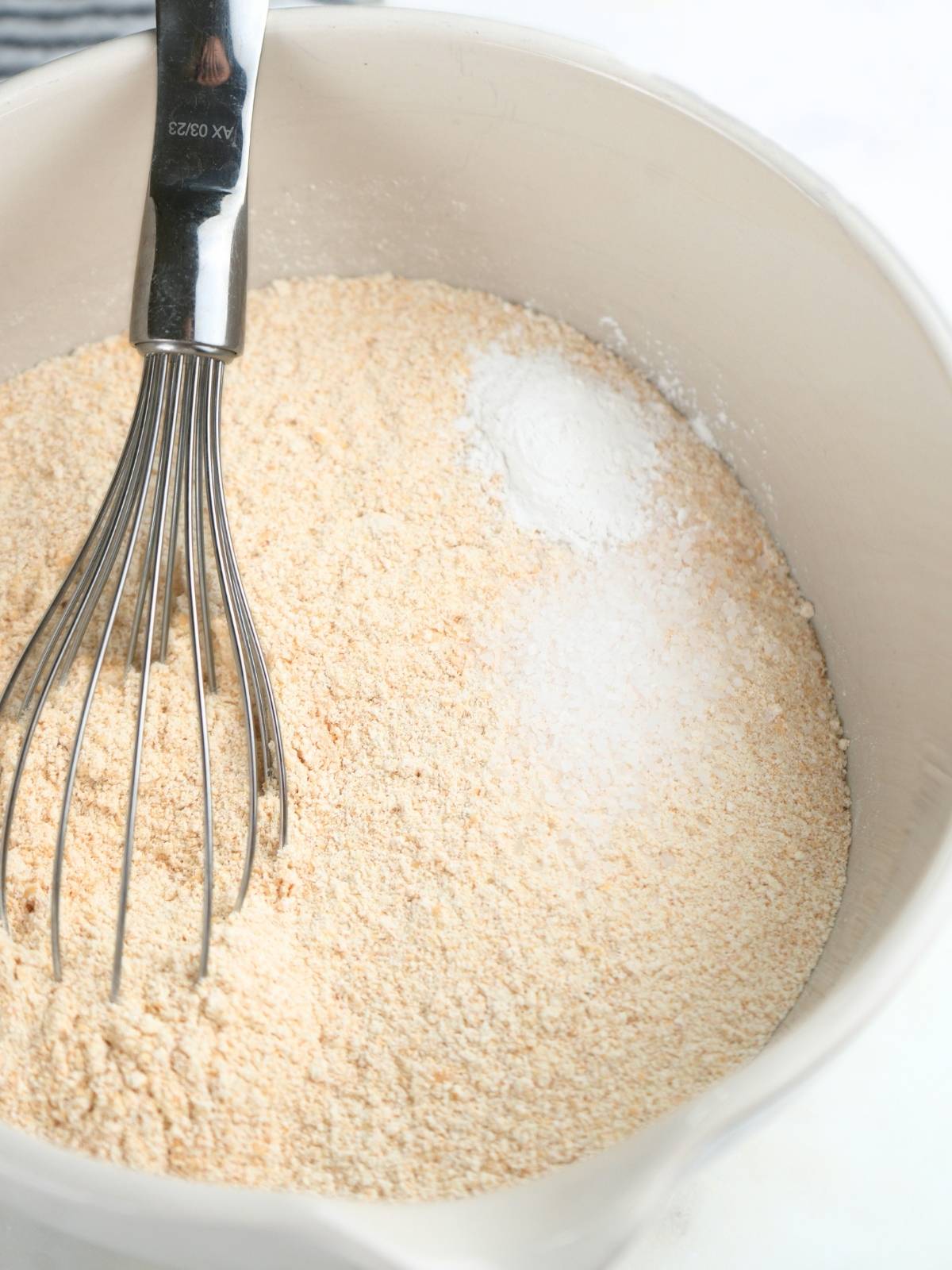 Dry ingredients in a mixing bowl with a wire whisk.