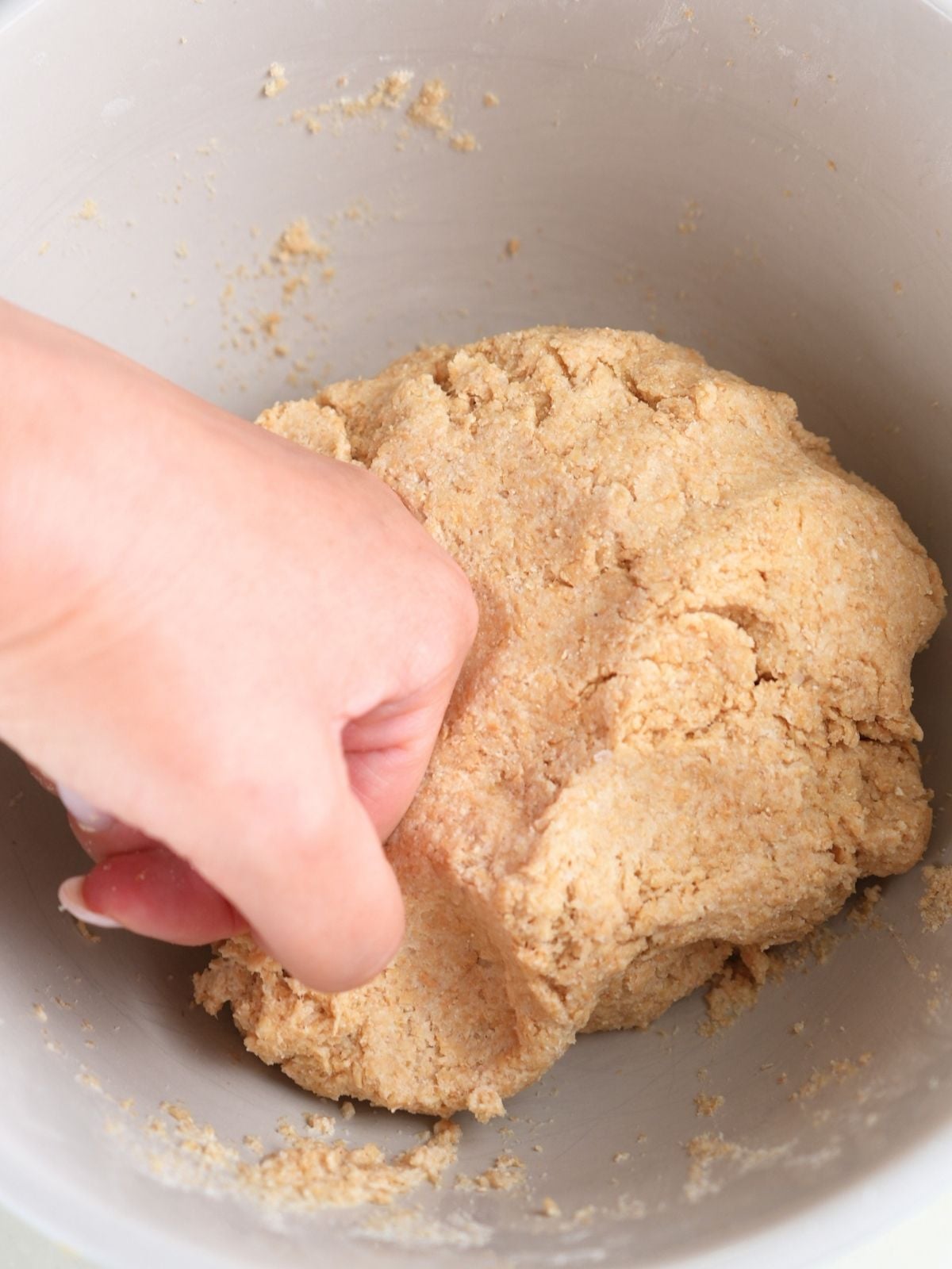 A hand kneading fresh-milled tortilla dough.