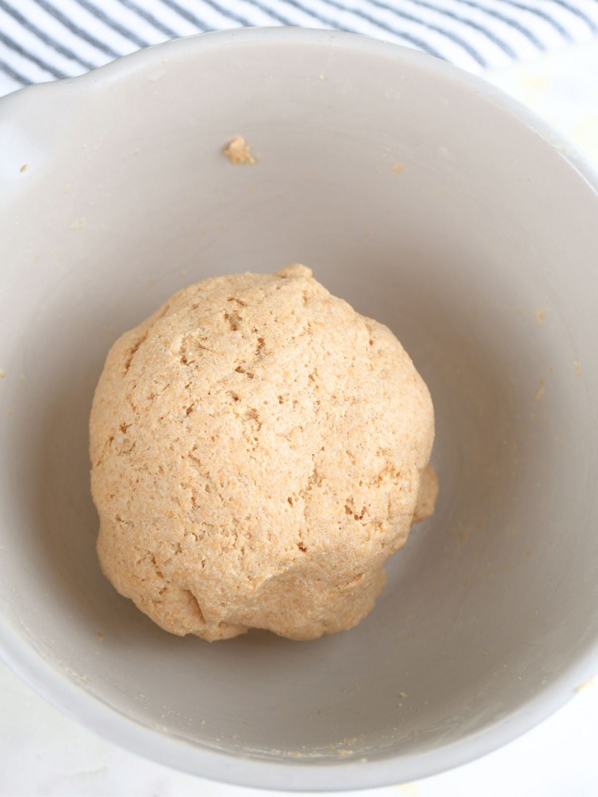 Dough shaped into a ball in a mixing bowl.