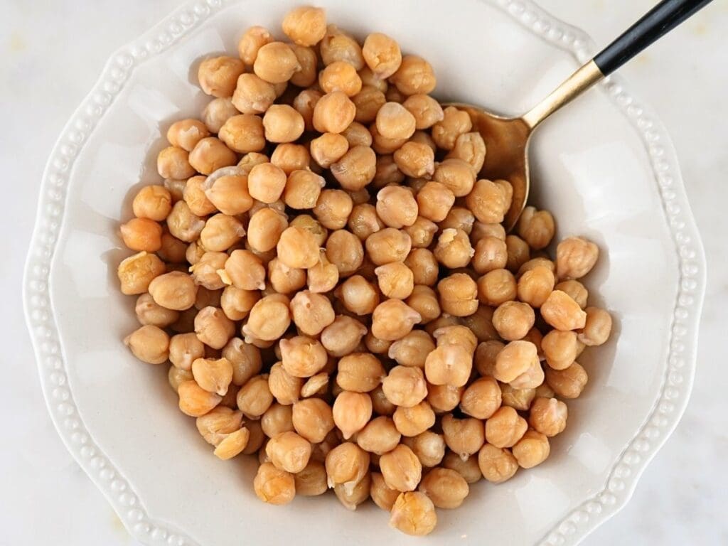 Cooked Instant Pot chickpeas in a bowl with a serving spoon.