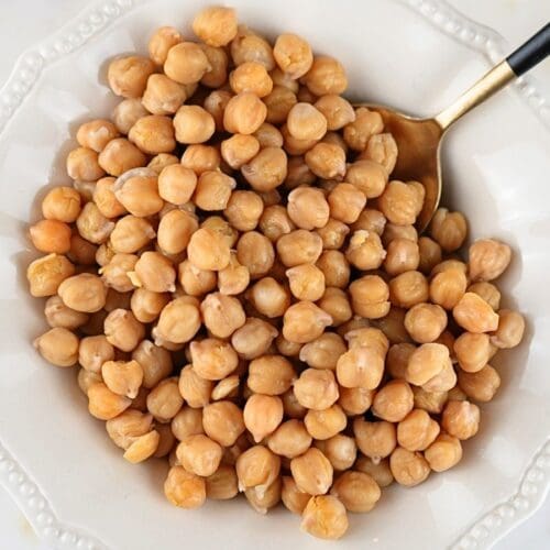 Cooked Instant Pot chickpeas in a bowl with a serving spoon.