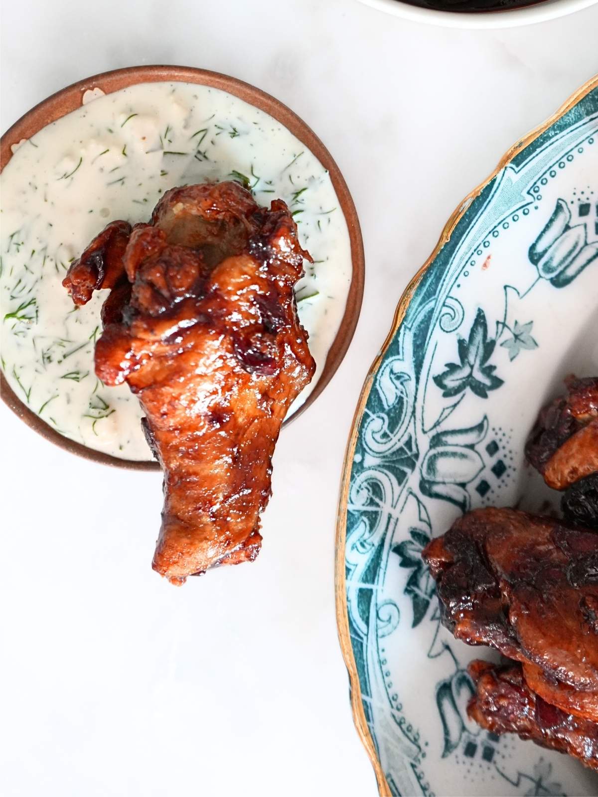 A chicken wing in a dish of cucumber ranch dressing.