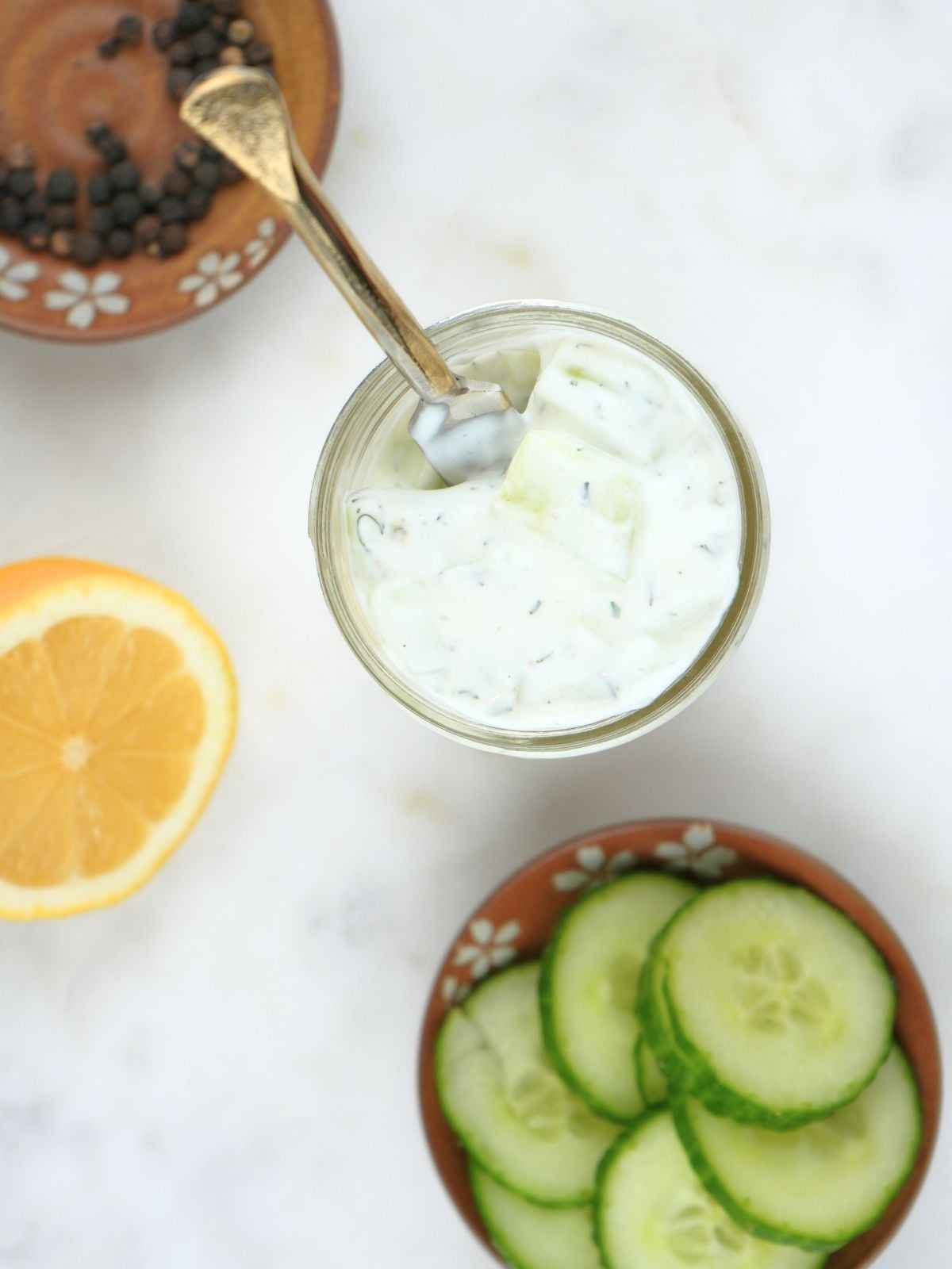 Greek yogurt cucumber ranch dressing in a jar shown with cucumbers and lemons.