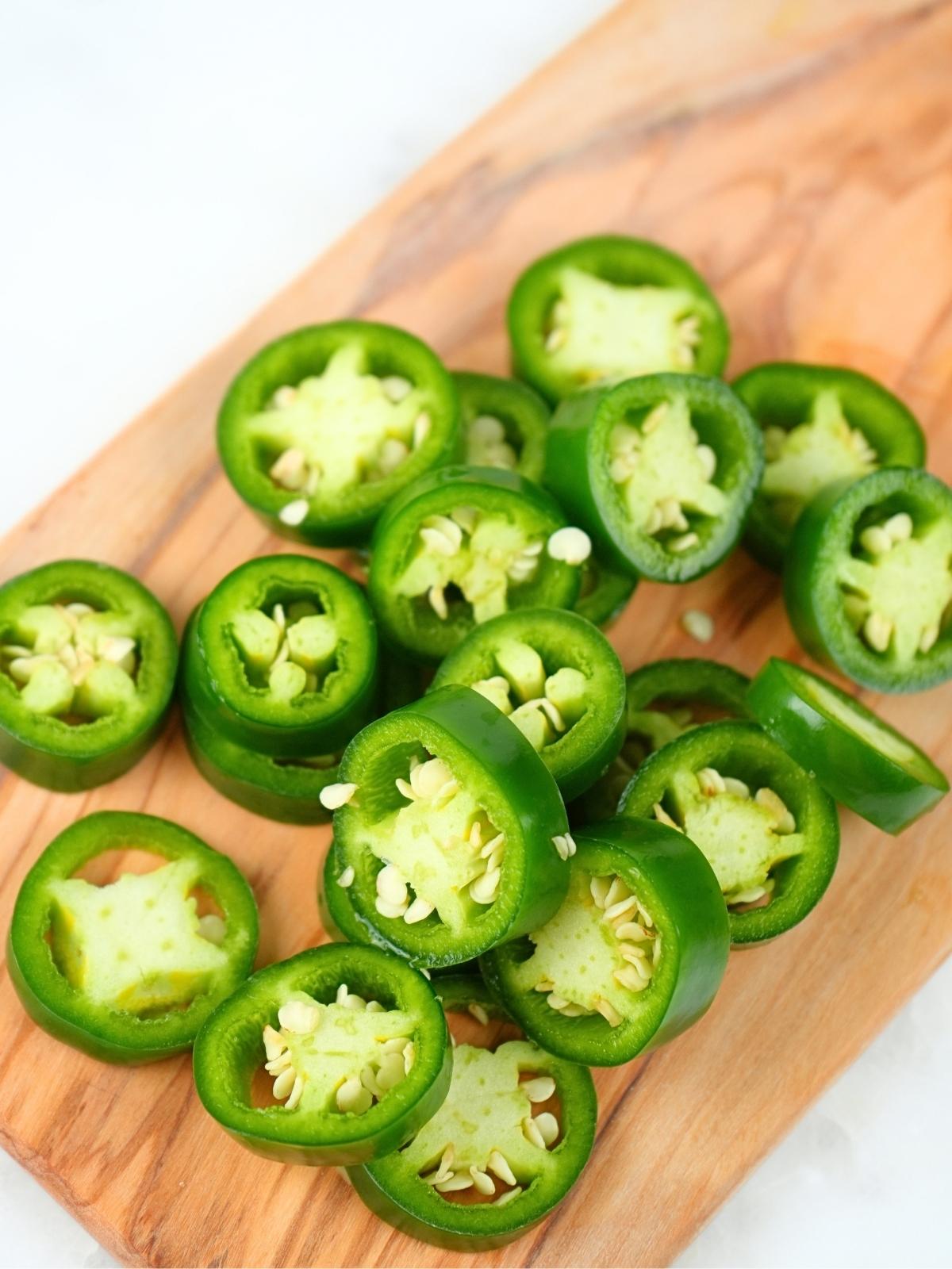 Sliced jalapeños on a cutting board.