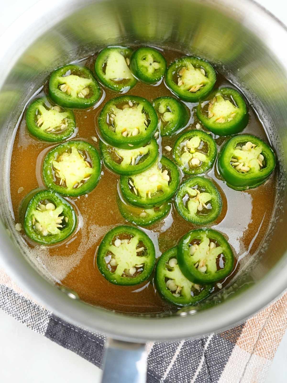 Honey and sliced jalapeños in a saucepan.
