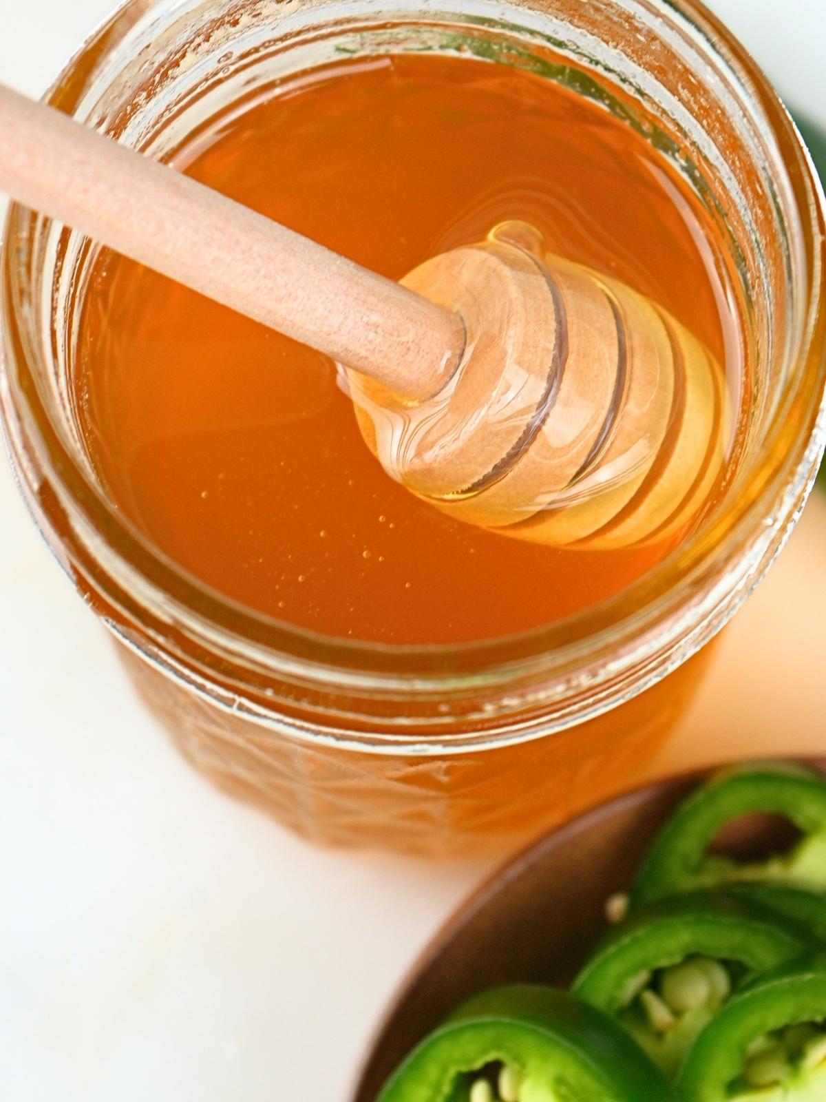 A honey stick in a jar of hot honey.