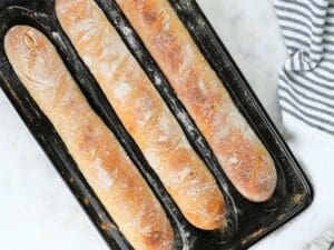 Three sourdough baguettes in a baguette pan.