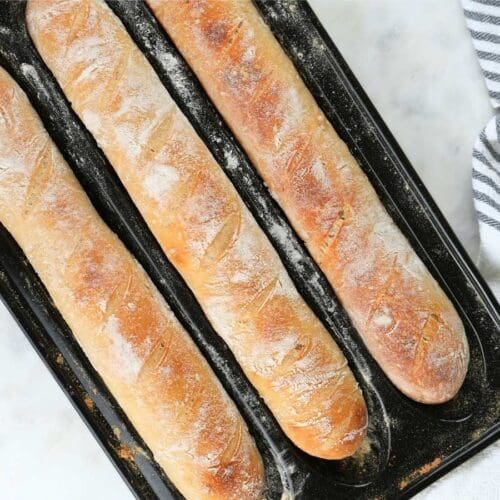 Three sourdough baguettes in a baguette pan.