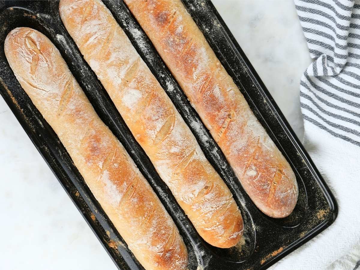Three sourdough baguettes in a baguette pan.