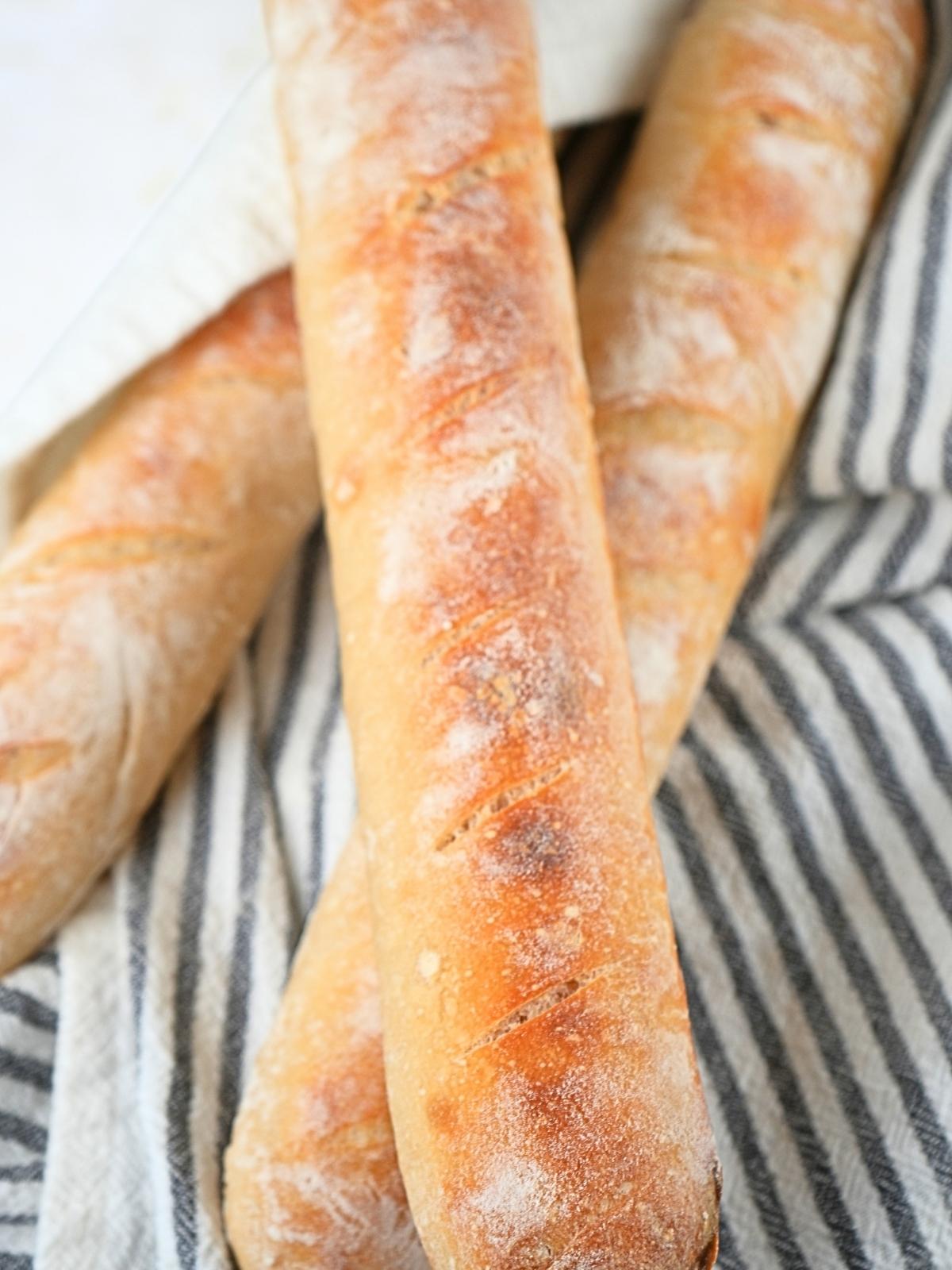 Sourdough baguettes on a decorative towel.