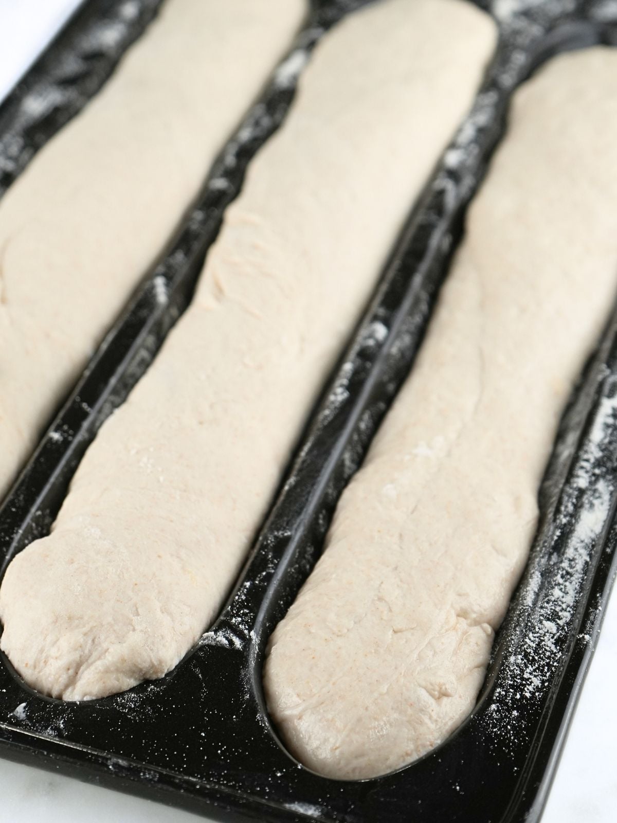 Shaped sourdough baguette dough in a baguette pan.