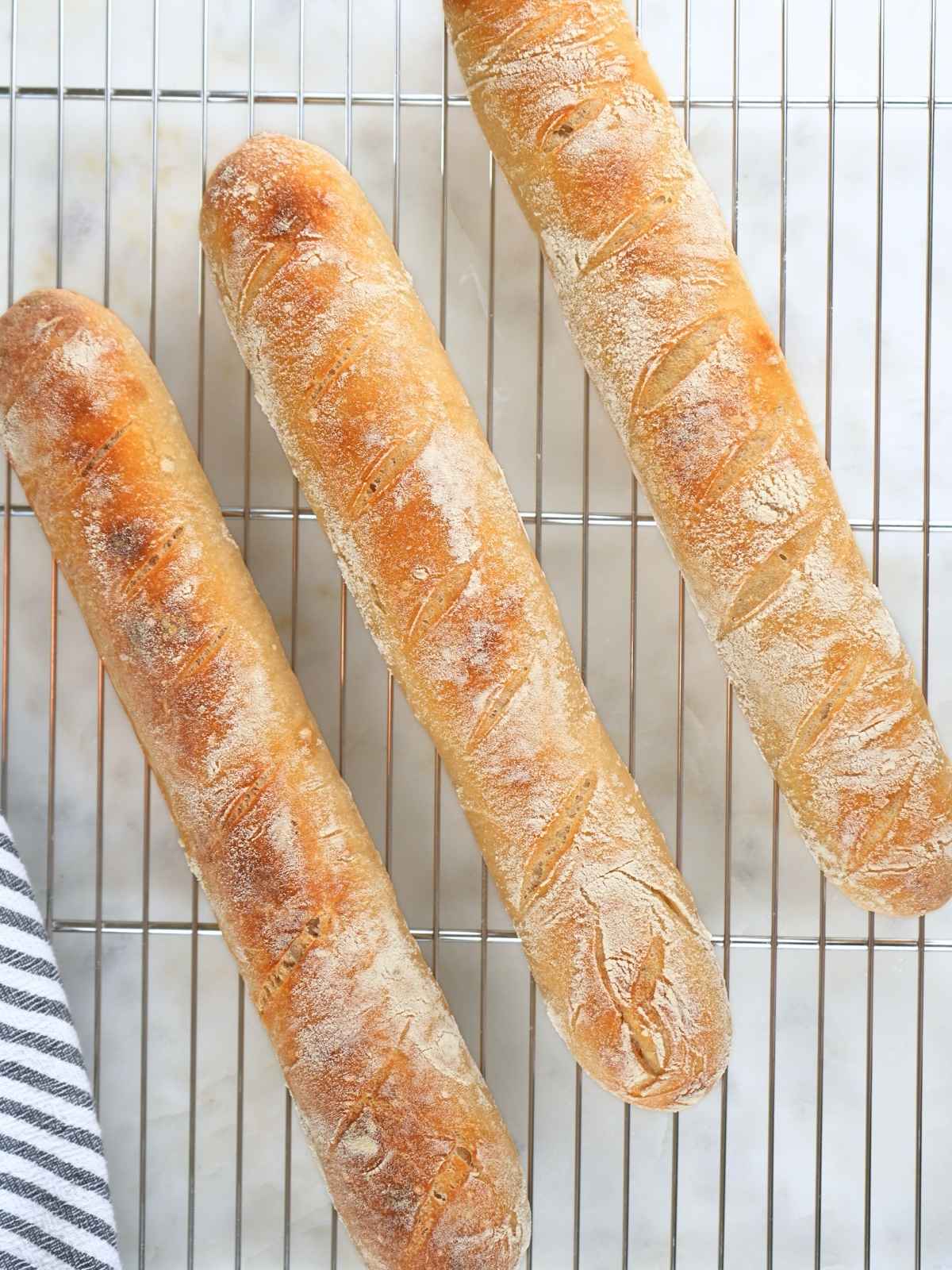 Finished sourdough baguettes on a cooling rack.
