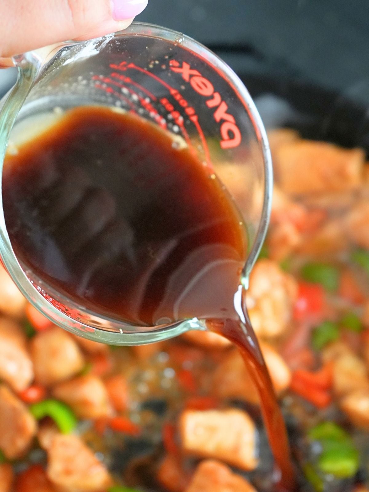 Sauce pouring into chicken and veggie stir fry.