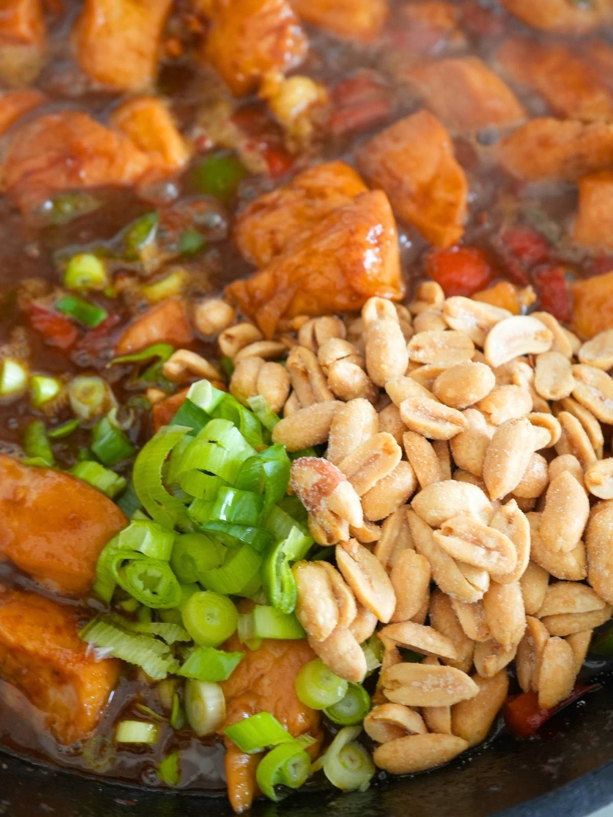 Peanuts and green onions cooking in stir fry.