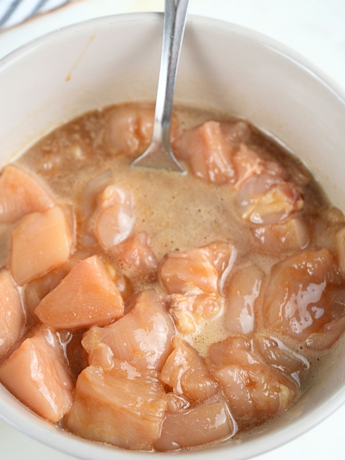 Chicken marinating in a bowl.