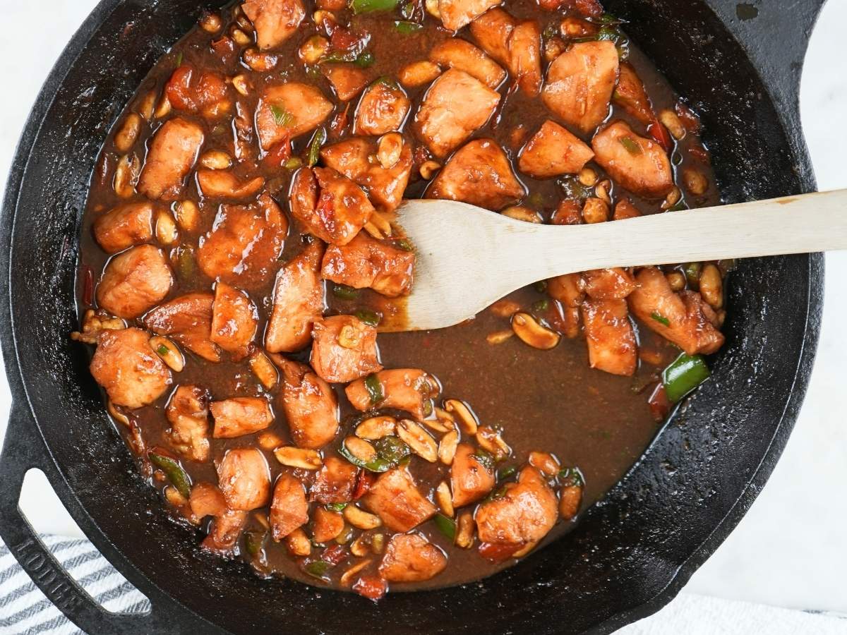 Kung pao chicken in a cast iron skillet next to a decorative towel.