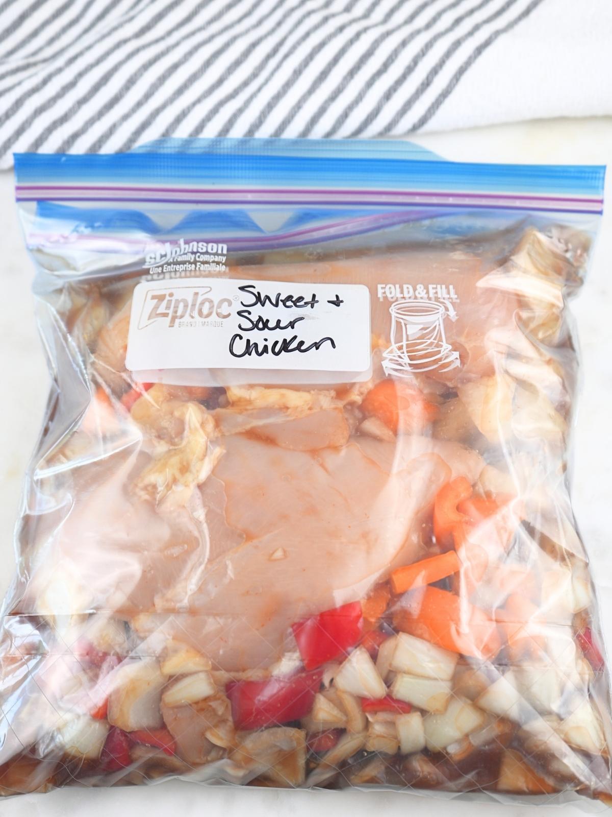 Sweet and sour chicken freezer meal in a labeled ziplock bag.